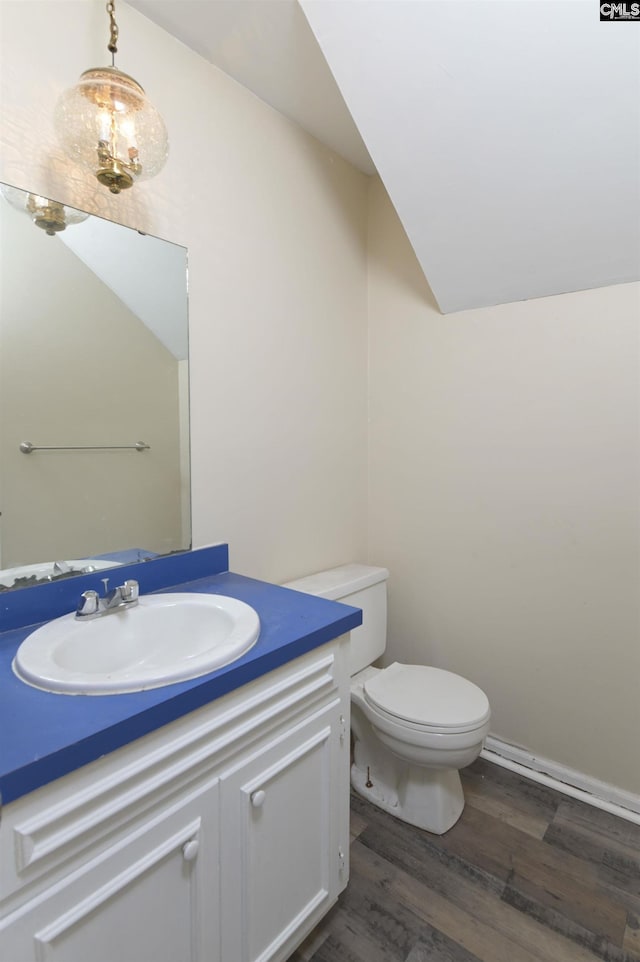 bathroom featuring wood-type flooring, toilet, vaulted ceiling, and vanity