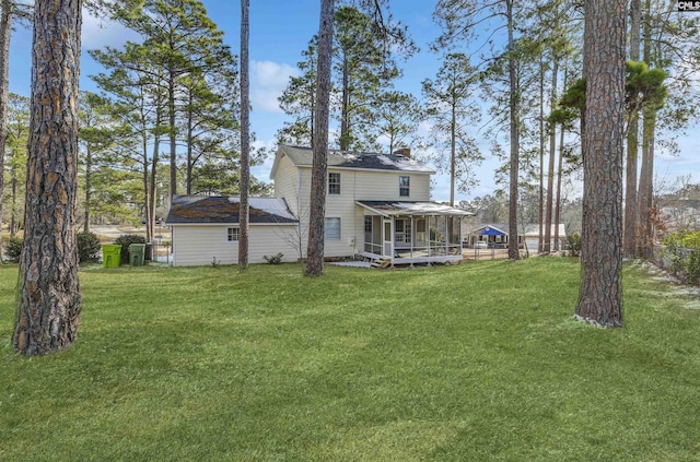 back of property with a sunroom and a yard