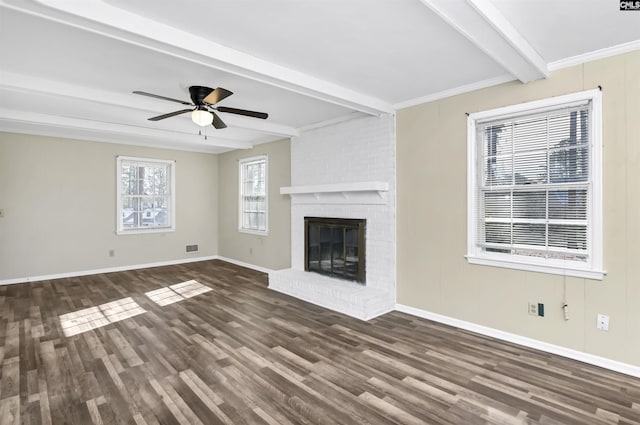 unfurnished living room with a fireplace, plenty of natural light, dark hardwood / wood-style floors, and beamed ceiling