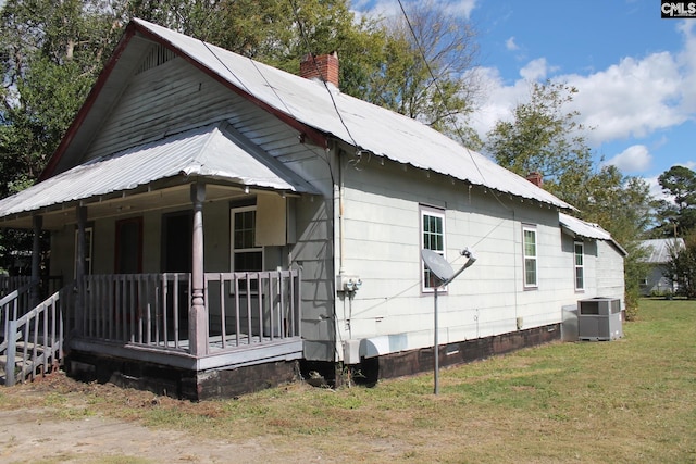 view of side of property featuring a yard, central air condition unit, and a porch