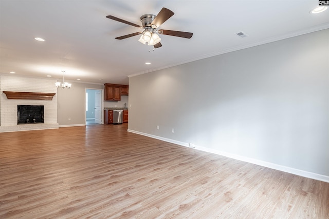 unfurnished living room featuring a brick fireplace, ceiling fan with notable chandelier, light hardwood / wood-style flooring, and ornamental molding