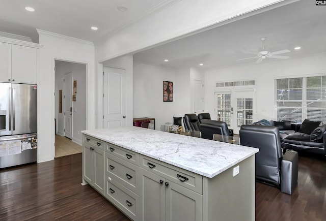 kitchen with gray cabinetry, ornamental molding, stainless steel fridge, a kitchen island, and light stone countertops