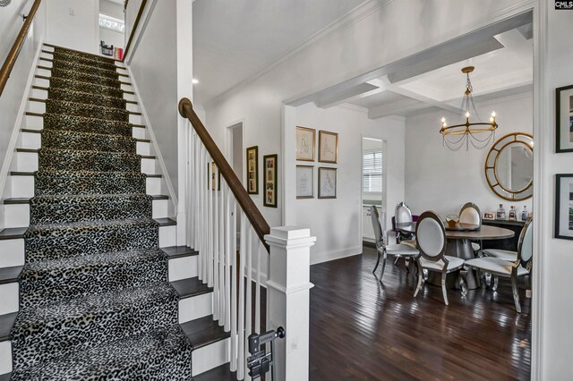 staircase with hardwood / wood-style floors, beamed ceiling, coffered ceiling, a notable chandelier, and crown molding