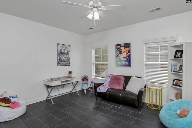 sitting room with ceiling fan and dark tile patterned flooring