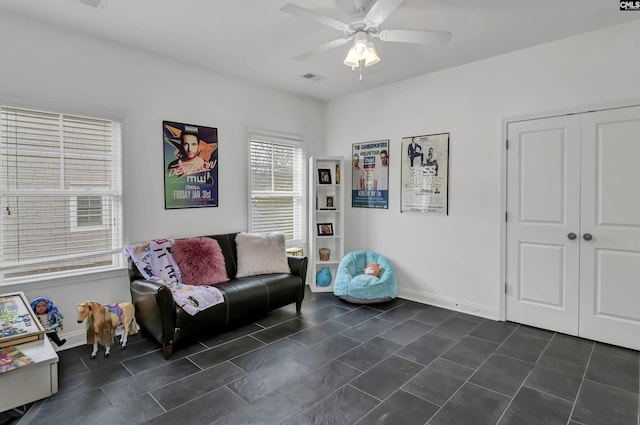 living area featuring ceiling fan and dark tile patterned flooring