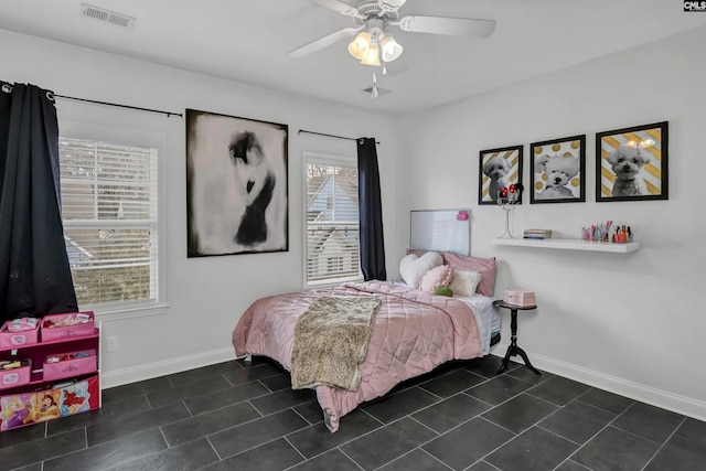 bedroom with multiple windows, dark tile patterned flooring, and ceiling fan