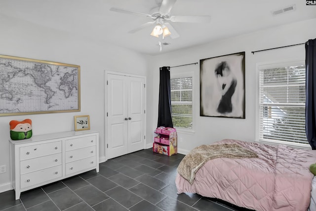 bedroom with ceiling fan, a closet, and dark tile patterned floors