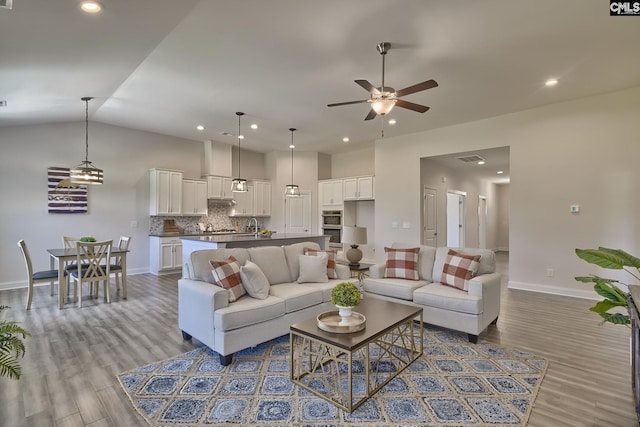 living room with ceiling fan, lofted ceiling, and light wood-type flooring