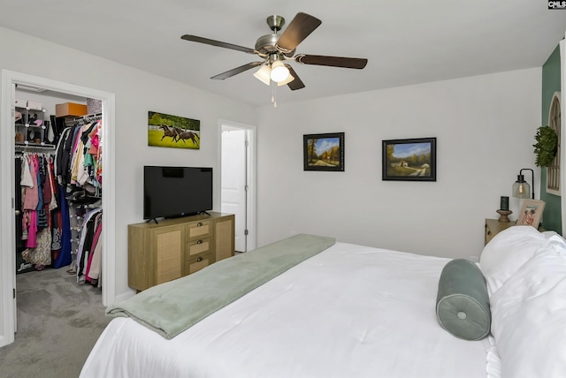 carpeted bedroom with a spacious closet, ceiling fan, and a closet