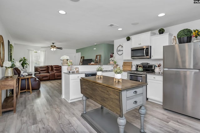 kitchen with appliances with stainless steel finishes, white cabinets, light wood-type flooring, and kitchen peninsula