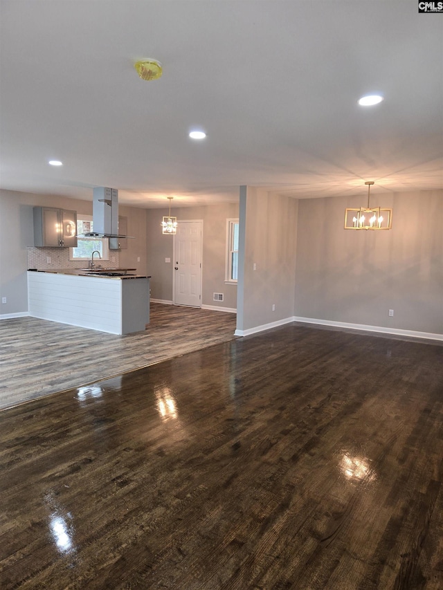 unfurnished living room featuring sink, a notable chandelier, and dark hardwood / wood-style flooring