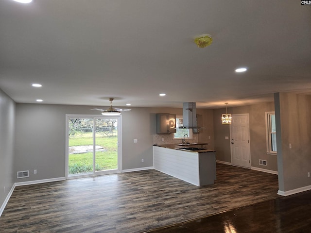 kitchen with dark hardwood / wood-style floors, island range hood, tasteful backsplash, sink, and kitchen peninsula