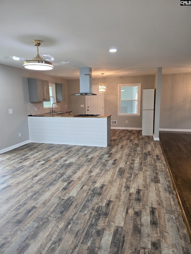 kitchen with island range hood, dark hardwood / wood-style flooring, kitchen peninsula, and backsplash