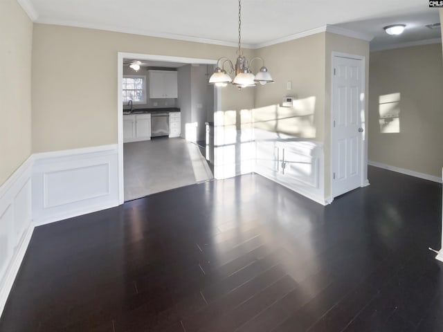 unfurnished dining area with dark wood-type flooring, ornamental molding, an inviting chandelier, and sink