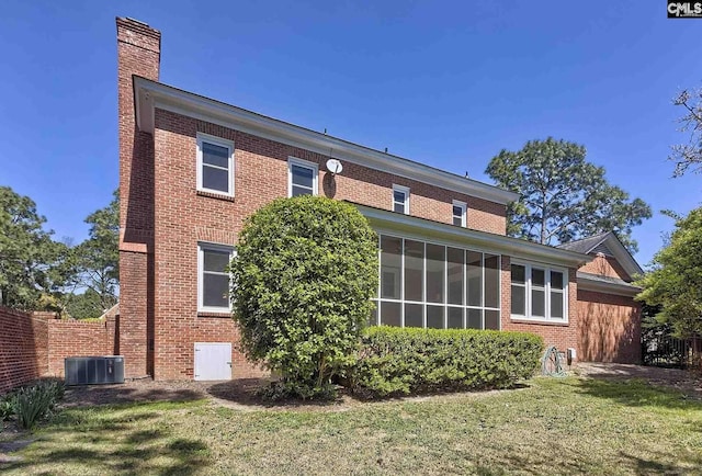 rear view of property with central AC, a yard, and a sunroom