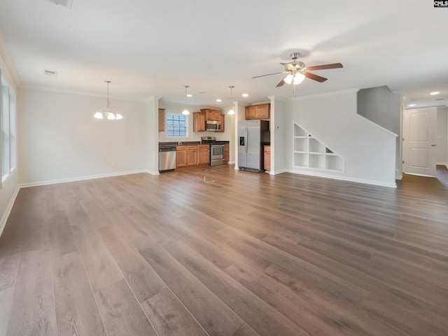 unfurnished living room featuring built in shelves, crown molding, ceiling fan with notable chandelier, and dark wood-type flooring