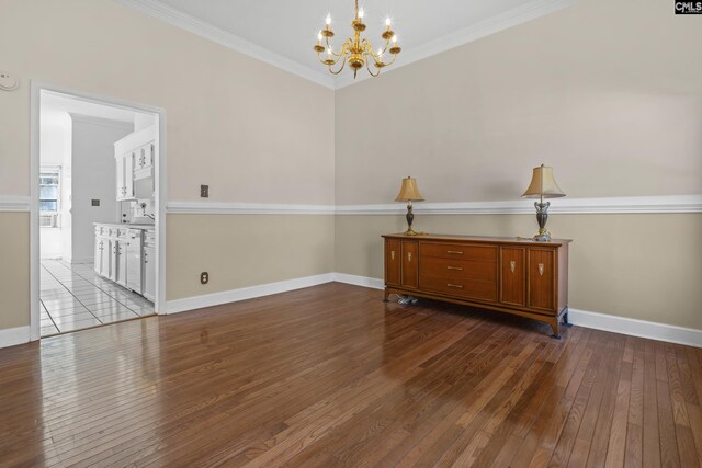 unfurnished room with hardwood / wood-style flooring, crown molding, and a chandelier