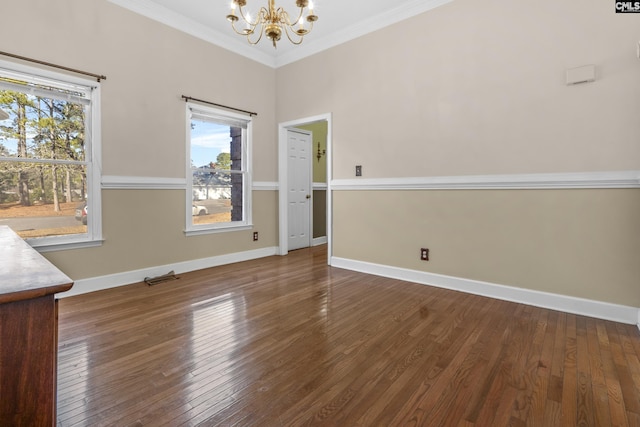 spare room featuring crown molding, dark hardwood / wood-style floors, and a chandelier