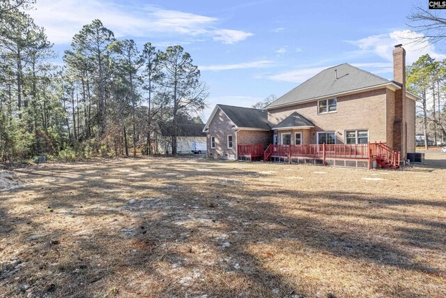 rear view of house featuring a wooden deck and a yard