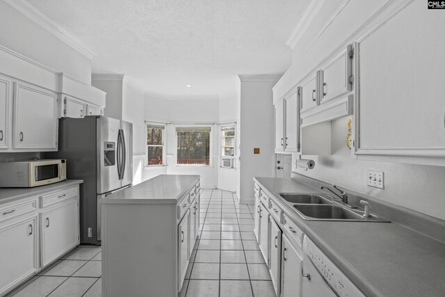 kitchen with white cabinetry, ornamental molding, a kitchen island, and light tile patterned floors