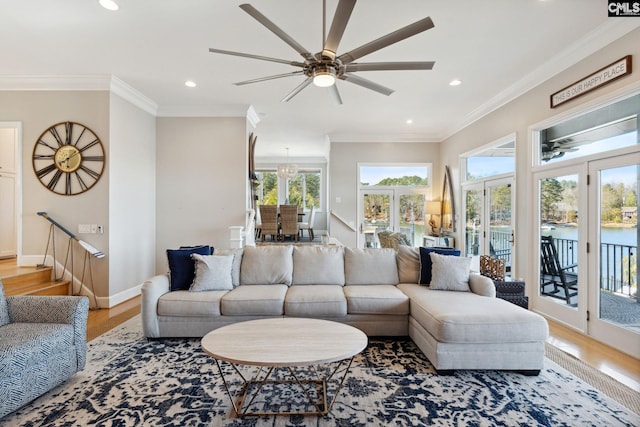 living room with ornamental molding, light hardwood / wood-style floors, ceiling fan, and a water view