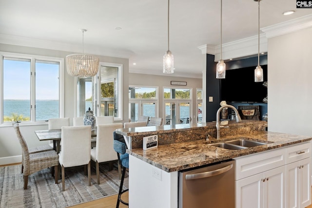 kitchen with sink, white cabinets, hanging light fixtures, stainless steel dishwasher, and a water view