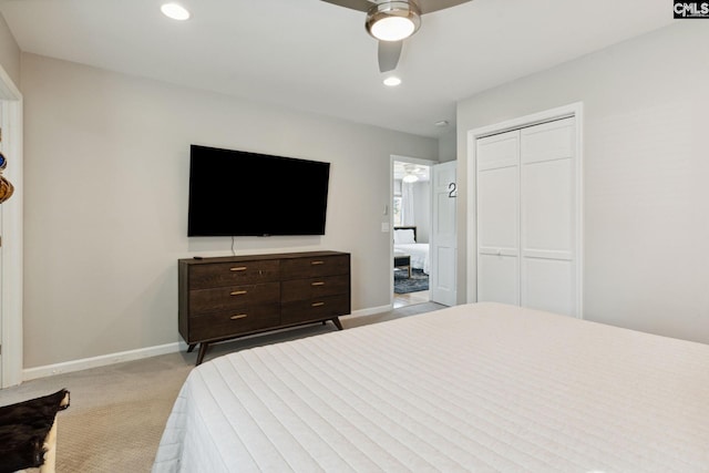 bedroom with ceiling fan, light colored carpet, and a closet