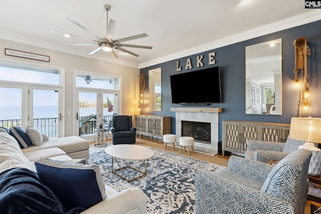 living room featuring crown molding, a fireplace, ceiling fan, and a water view