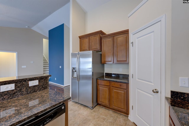 kitchen featuring lofted ceiling, dark stone counters, and appliances with stainless steel finishes