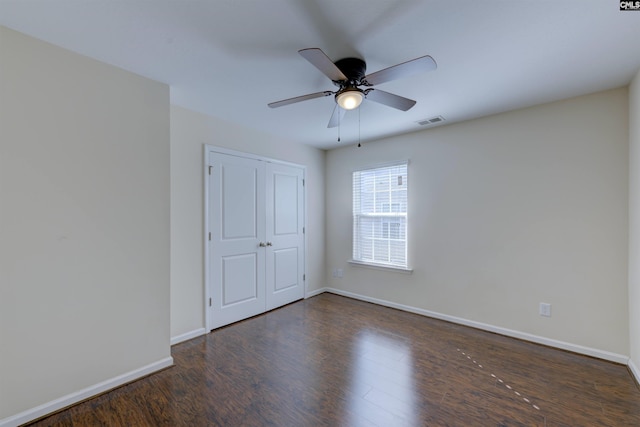 spare room featuring dark wood-type flooring and ceiling fan