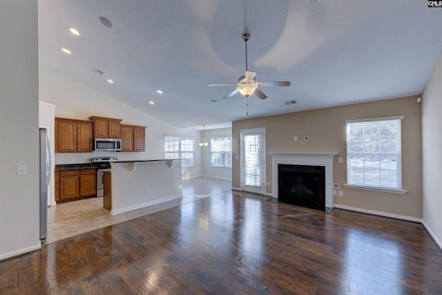 unfurnished living room featuring ceiling fan, wood-type flooring, and vaulted ceiling