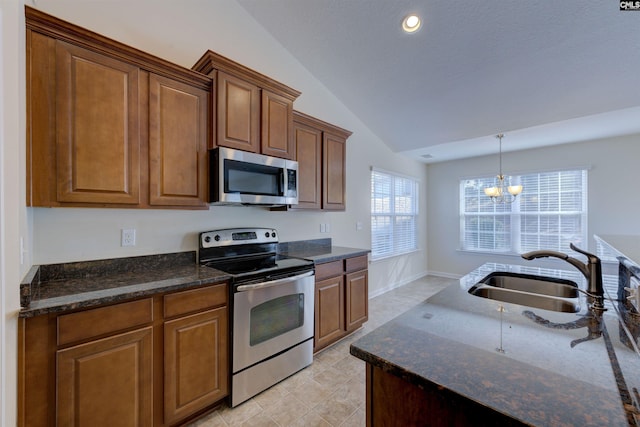 kitchen featuring sink, vaulted ceiling, dark stone counters, and appliances with stainless steel finishes