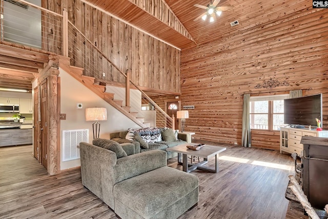 living room featuring hardwood / wood-style flooring, wooden ceiling, high vaulted ceiling, and wood walls