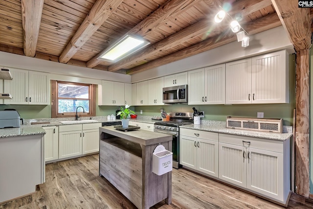 kitchen with sink, white cabinetry, light stone counters, light hardwood / wood-style flooring, and appliances with stainless steel finishes