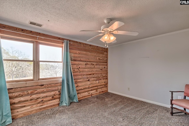 empty room featuring rustic walls, crown molding, a textured ceiling, carpet floors, and ceiling fan