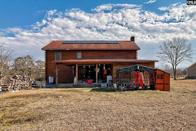 back of house featuring a lawn and solar panels