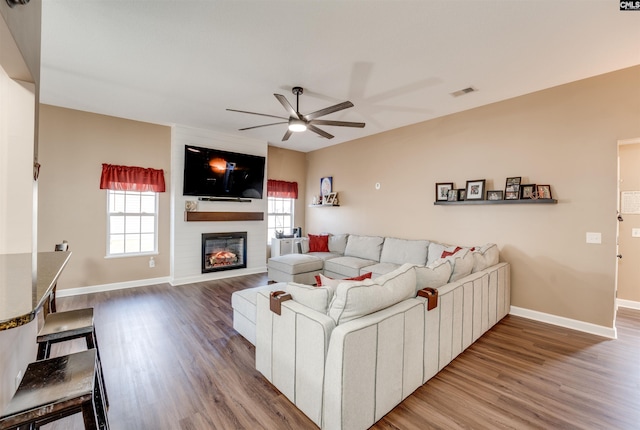 living room with hardwood / wood-style floors, a large fireplace, and ceiling fan