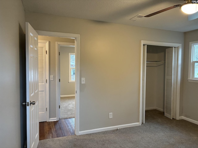 unfurnished bedroom with ceiling fan, dark carpet, a closet, and a textured ceiling