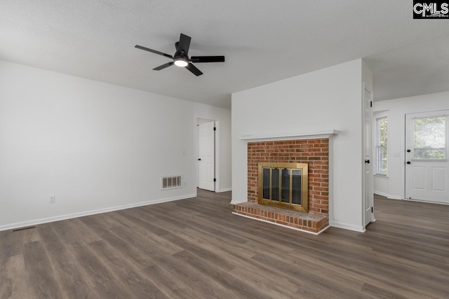 unfurnished living room with ceiling fan, a textured ceiling, a fireplace, and dark hardwood / wood-style flooring