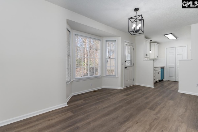 unfurnished dining area featuring an inviting chandelier, dark hardwood / wood-style floors, and a textured ceiling