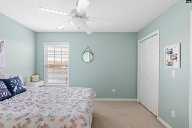 bedroom with light colored carpet, a textured ceiling, ceiling fan, and a closet