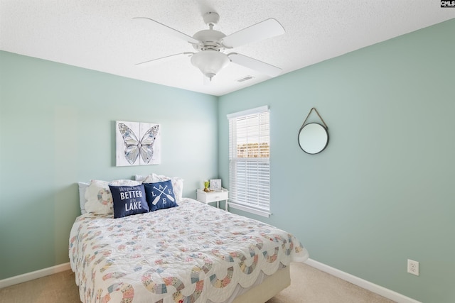 bedroom featuring a textured ceiling, light colored carpet, and ceiling fan