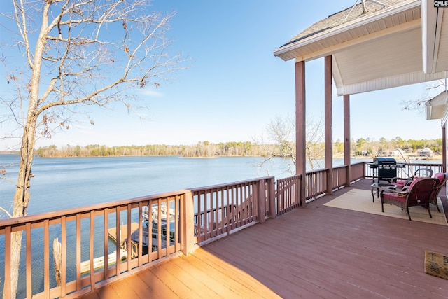 wooden deck featuring a water view and a grill