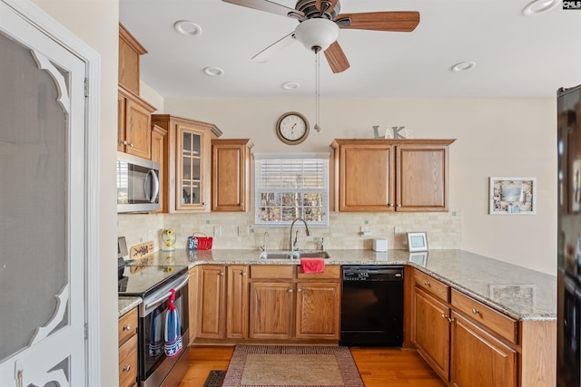 kitchen featuring sink, backsplash, stainless steel appliances, light stone countertops, and kitchen peninsula