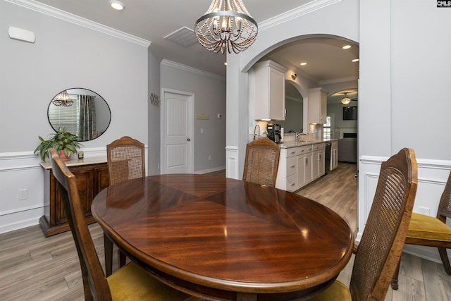 dining space featuring crown molding, sink, ceiling fan with notable chandelier, and light hardwood / wood-style floors