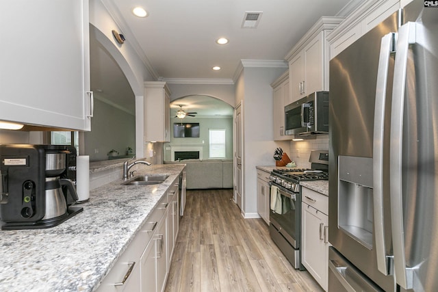 kitchen featuring white cabinetry, sink, light hardwood / wood-style floors, stainless steel appliances, and light stone countertops