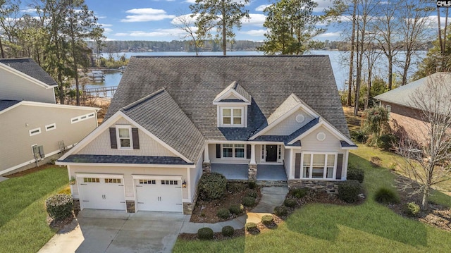 view of front of home featuring a water view, a garage, and a front lawn