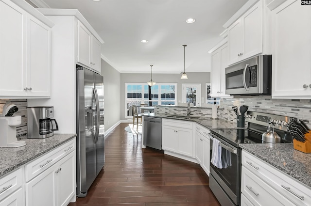 kitchen featuring sink, dark stone countertops, hanging light fixtures, stainless steel appliances, and white cabinets