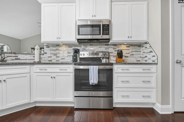 kitchen with white cabinetry, stainless steel appliances, and dark stone counters