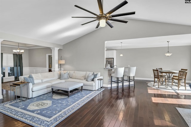 living room with ceiling fan with notable chandelier, dark hardwood / wood-style floors, vaulted ceiling, and ornate columns